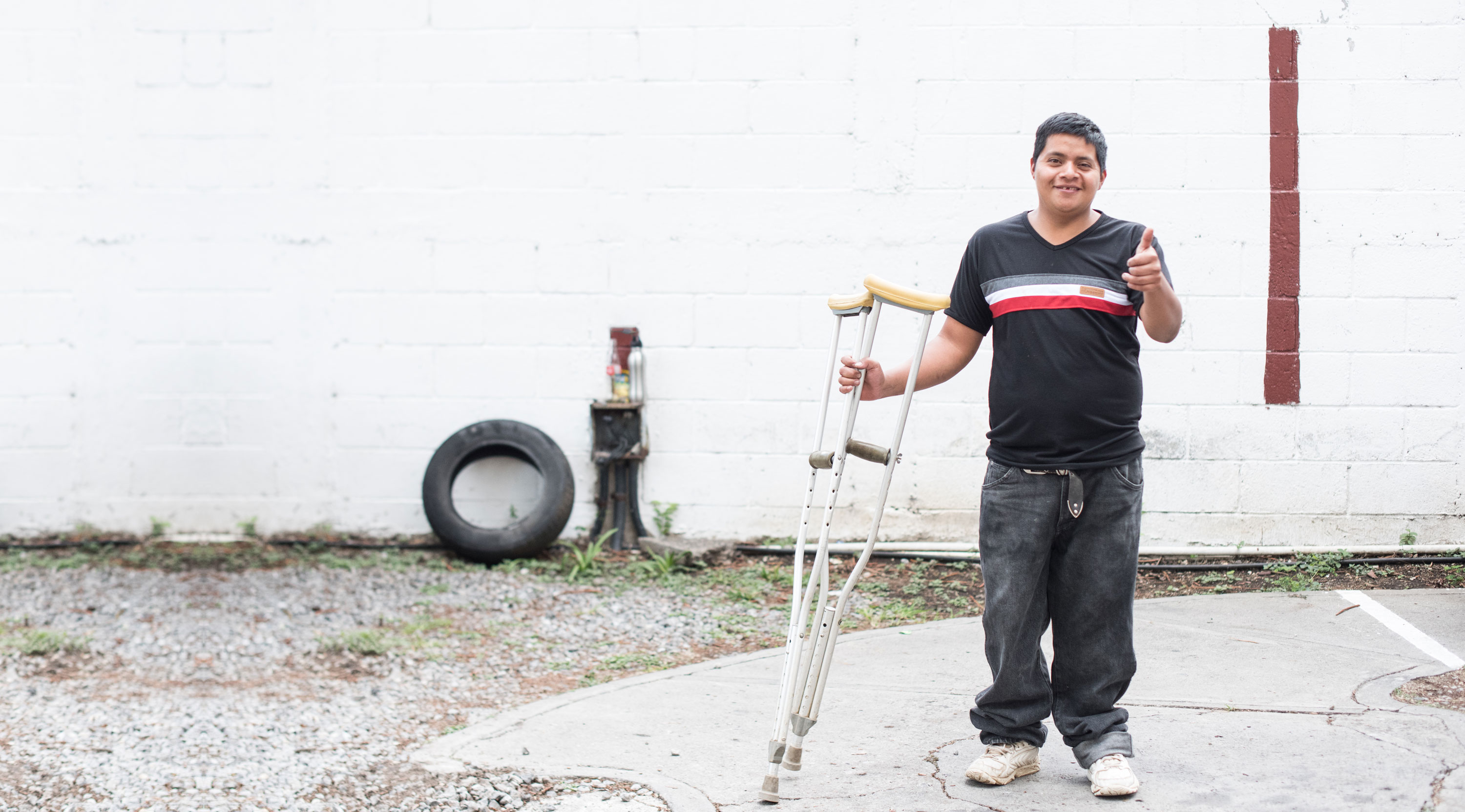 image of a young man standing holding crutches